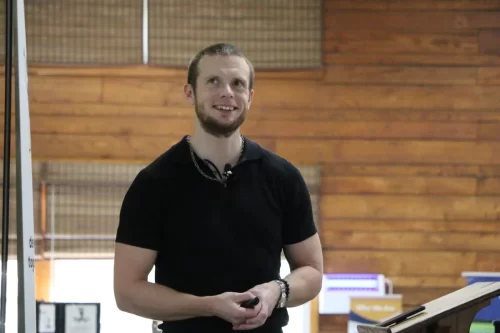 Russell-smiling-at-the-camera-with-his-hands-together